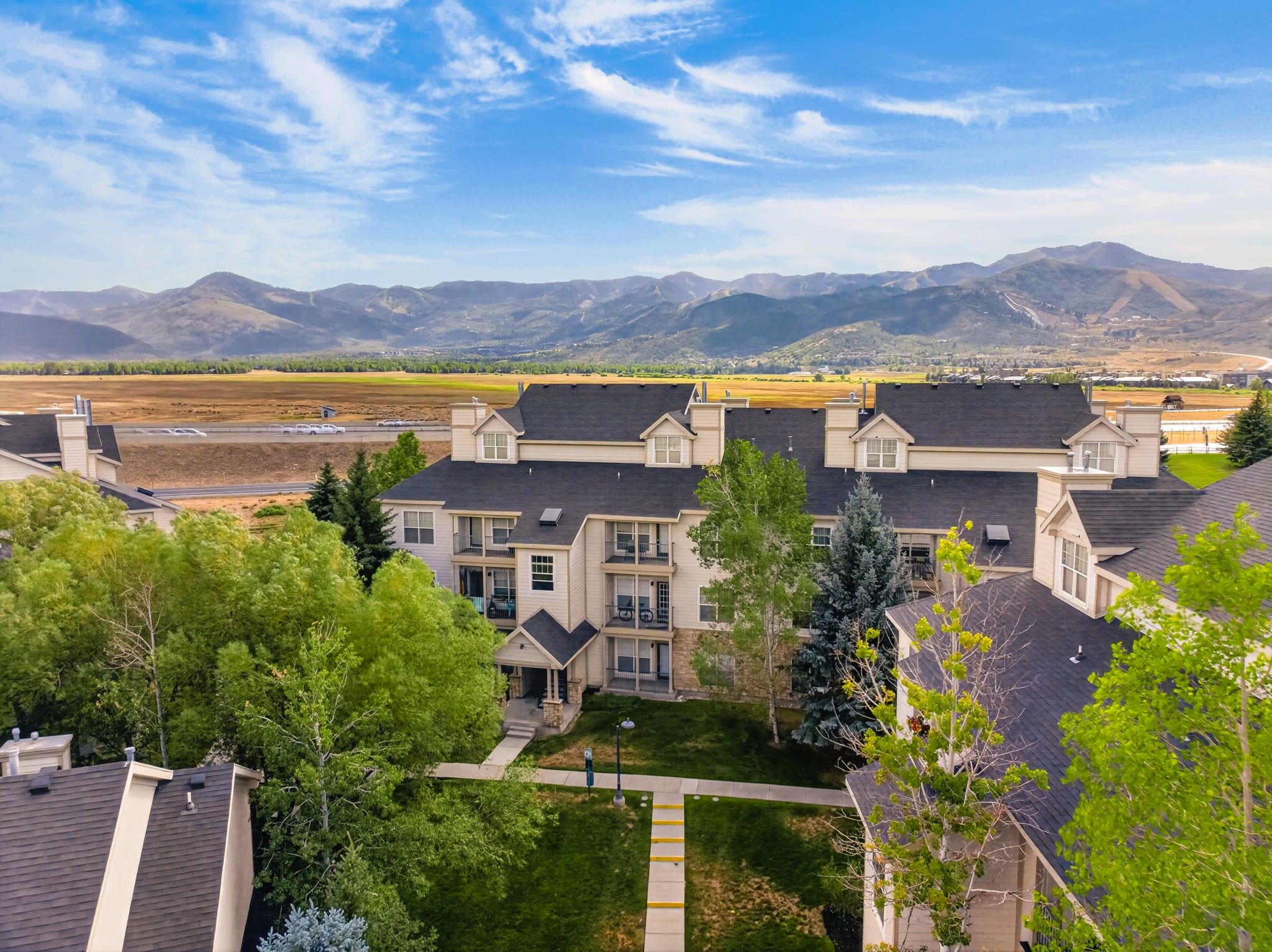 A residential area with multi-story houses, a clear sky, and mountains in the background.