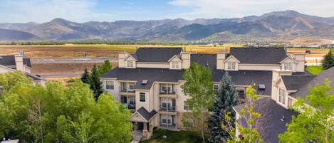 A residential area with multi-story houses, a clear sky, and mountains in the background.