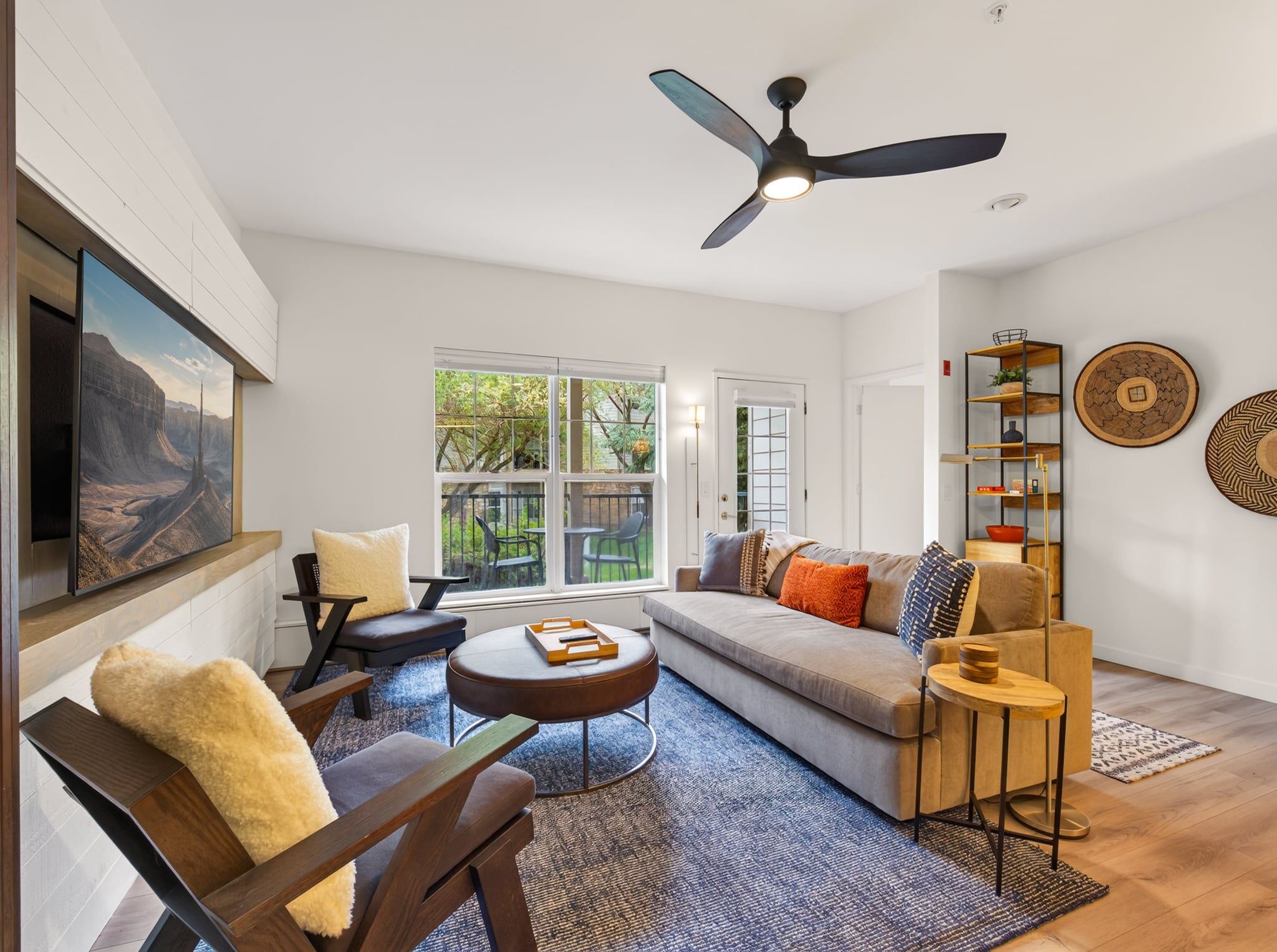 A modern living room with a sofa, chairs, a coffee table, and a ceiling fan.
