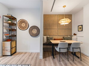 A dining area with a wooden table, two chairs, a bench with cushions, and a hanging pendant light. - Cute Updated 1BR Condo in Park City, 30 Night Min (Park City)