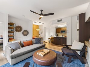 A modern living room with a sofa, ottoman, and coffee table. There is a dining area with a bar and kitchen in the background. - Cute Updated 1BR Condo in Park City, 30 Night Min (Park City)