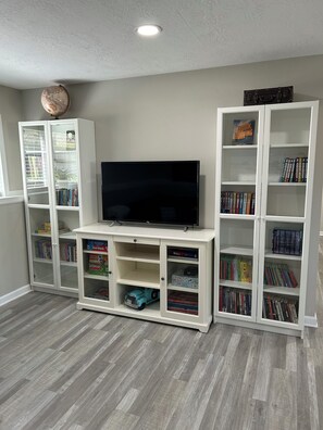 A living room with a flat-screen TV, built-in bookshelves, and a globe on the ceiling.