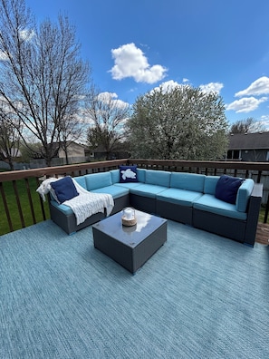 A covered outdoor seating area with a sectional sofa and a coffee table.