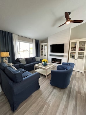 A modern living room with a sofa set, a coffee table, and a television mounted on the wall.