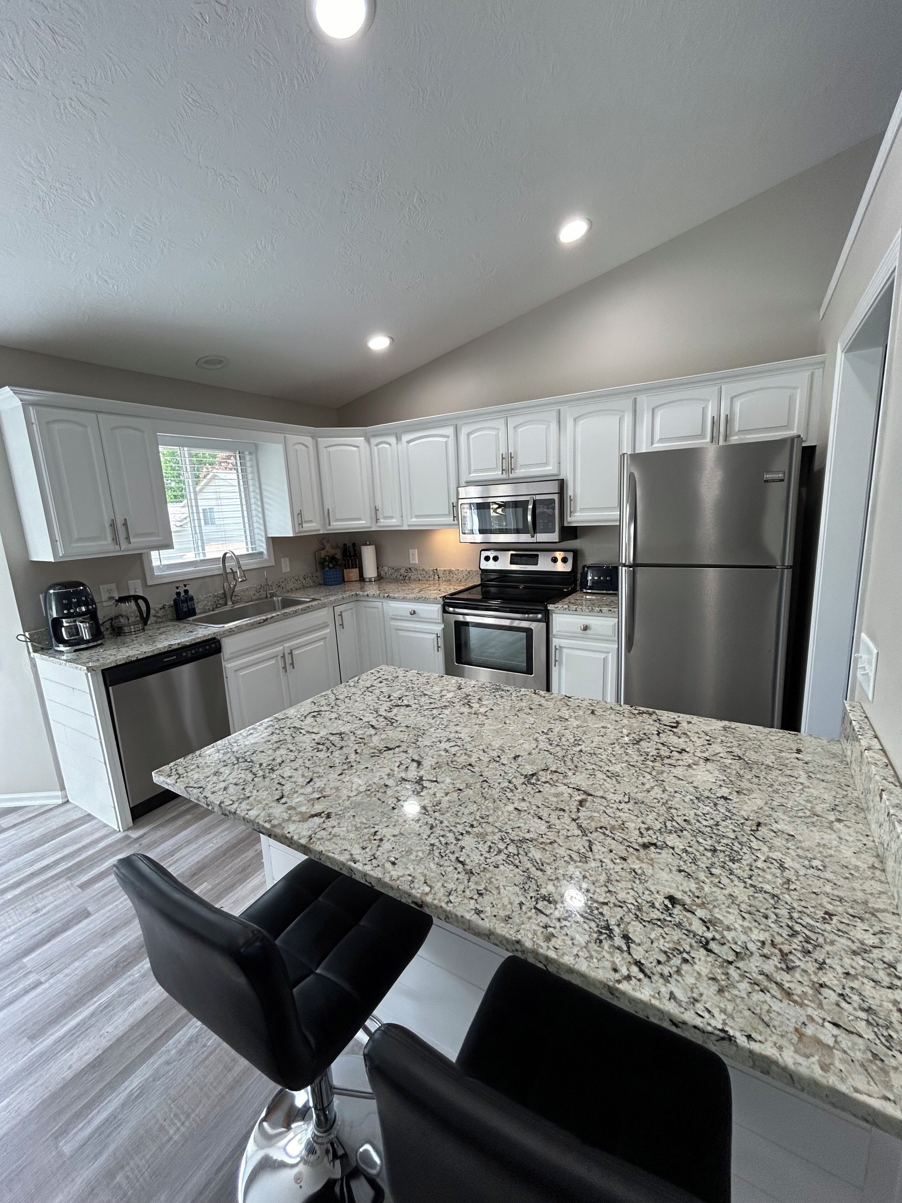 A modern kitchen with white cabinetry, stainless steel appliances, and a granite countertop.
