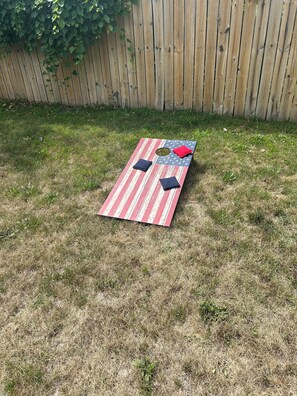 Uma mesa de piquenique com toalha listrada, dois jogos americanos pretos e um guardanapo vermelho.