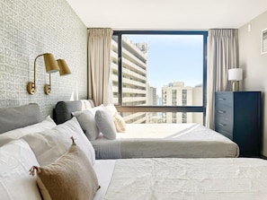 A hotel room with two beds, a large window with a view of buildings, a wardrobe, and a lamp. - 21F-Beautiful Waikiki-1BR Condo-Near Beach w/ Diamond Head & Partial Ocean Views (Honolulu)