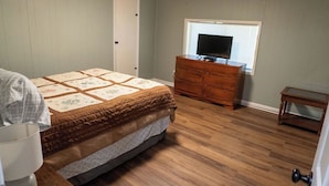 Un dormitorio con cama, cómoda y televisor sobre un mueble.