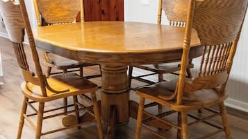 A dining table with six chairs, a wooden floor, and a door in the background.
