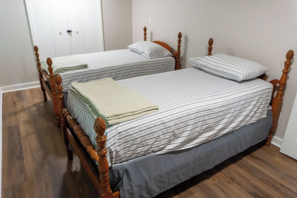 Une chambre avec deux lits en bois, chacun recouvert d’une courtepointe à rayures et agrémenté d’oreillers.