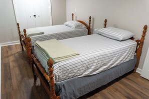 Ein Zimmer mit zwei Holzbetten, jeweils mit einem gestreiften Bettbezug und Kissen.
