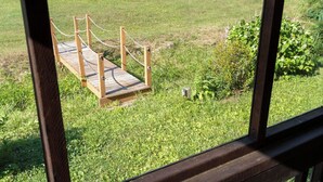 Un puente de madera sobre un césped, con un sendero al fondo.