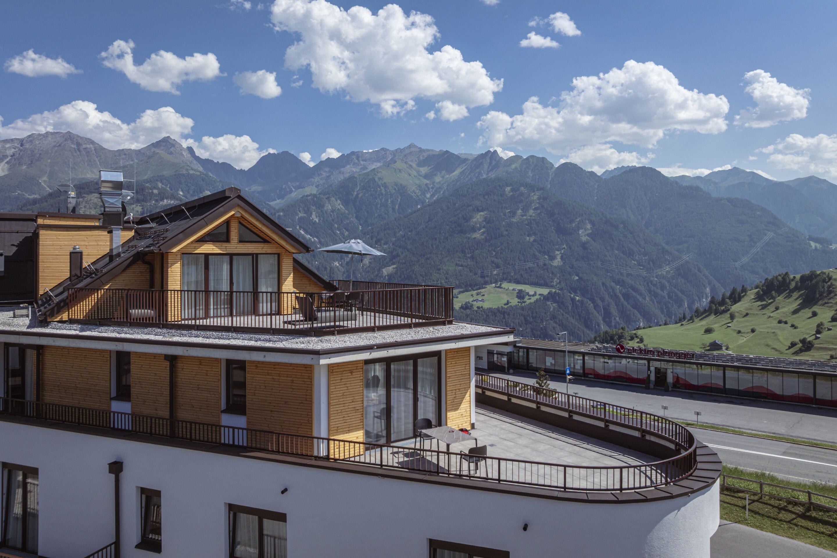 A modern building with a balcony overlooking a mountainous landscape.