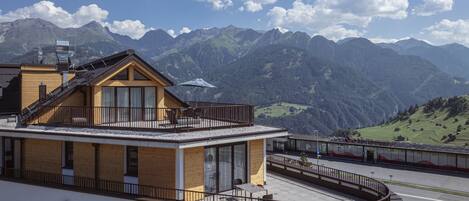 A modern building with a balcony overlooking a mountainous landscape.
