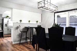 Ett modernt kök med matplats, utrustat med ett inbyggt kylskåp, ett matbord med stolar och en hänglampa.