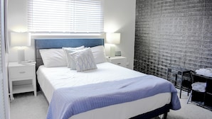 A bedroom with a bed, nightstands, a lamp, a clock, and a black textured wall. - Serene Tuxedo 3-bedroom townhome with AC in charming Grandview (Grandview)