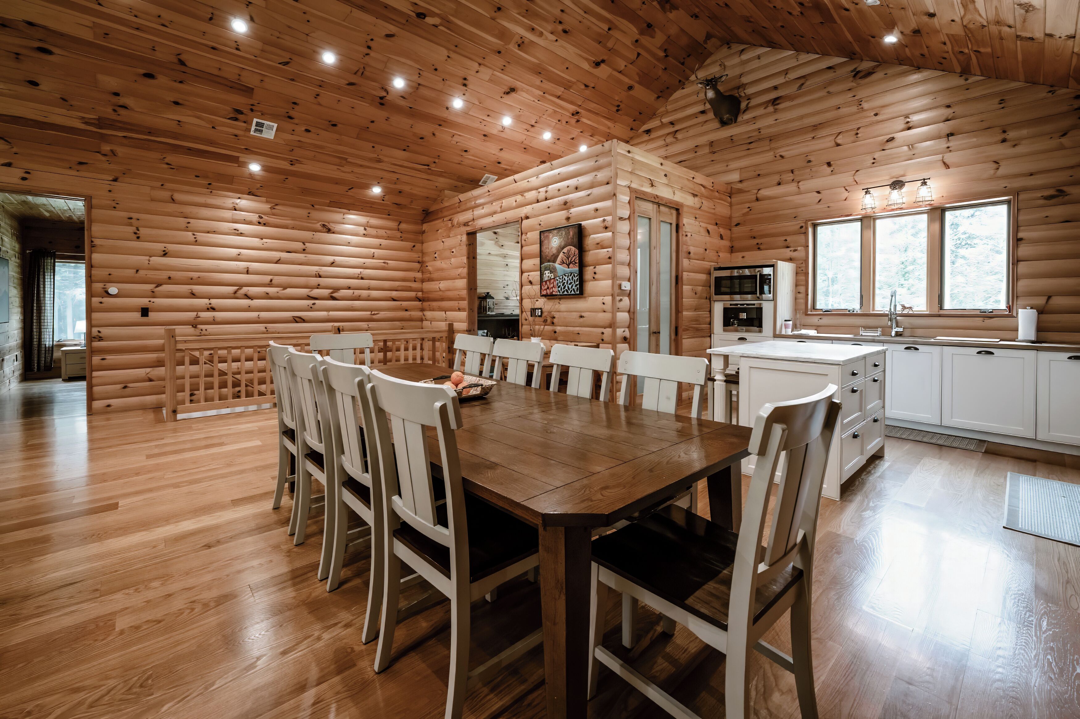 L’intérieur d’une cabane en rondins comprend un coin repas, une cuisine et une grande fenêtre.