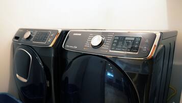 Vue de face d’un lave-linge noir à chargement frontal, doté d’un panneau de commande et d’un écran numérique.