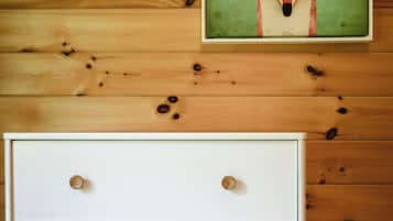 Une commode blanche avec des boutons ronds, placée contre un mur en bois orné d’un tableau représentant un renard.