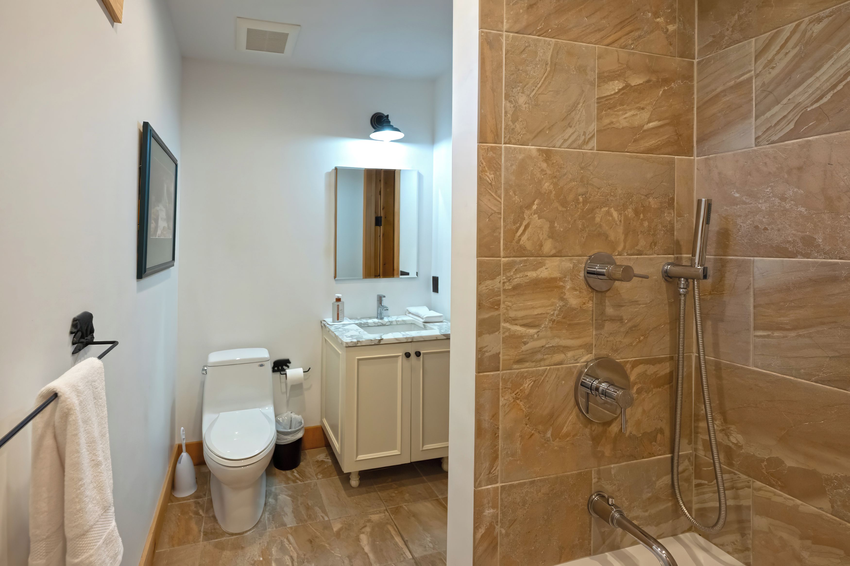 A bathroom with a toilet, sink, mirror, and shower.