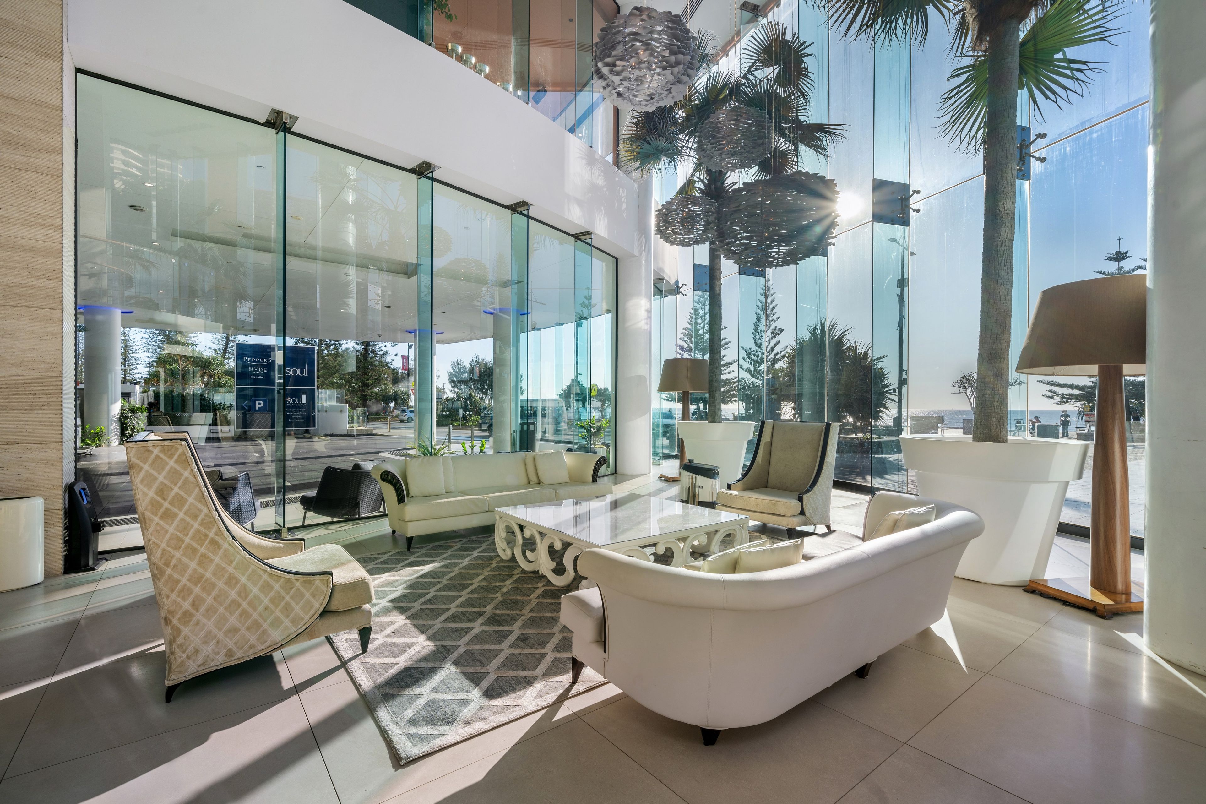 Eine moderne Lobby mit Glaswand, weißen Möbeln und Blick ins Freie.