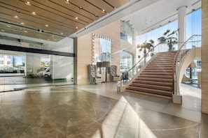 Eine großzügige Lobby mit einer zentralen Treppe, Glaswänden und modernem Design.