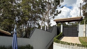 Piscina com borda azulejada, rodeada por espreguiçadeiras e um pérgola.