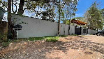 A residential area with a paved driveway, a covered outdoor seating area, and a gated entrance.