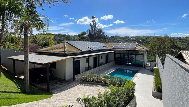 Uma casa moderna com piscina, painéis solares e vista para o campo.