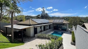 Ett modernt hus med en swimmingpool, solpaneler och utsikt över landsbygden.