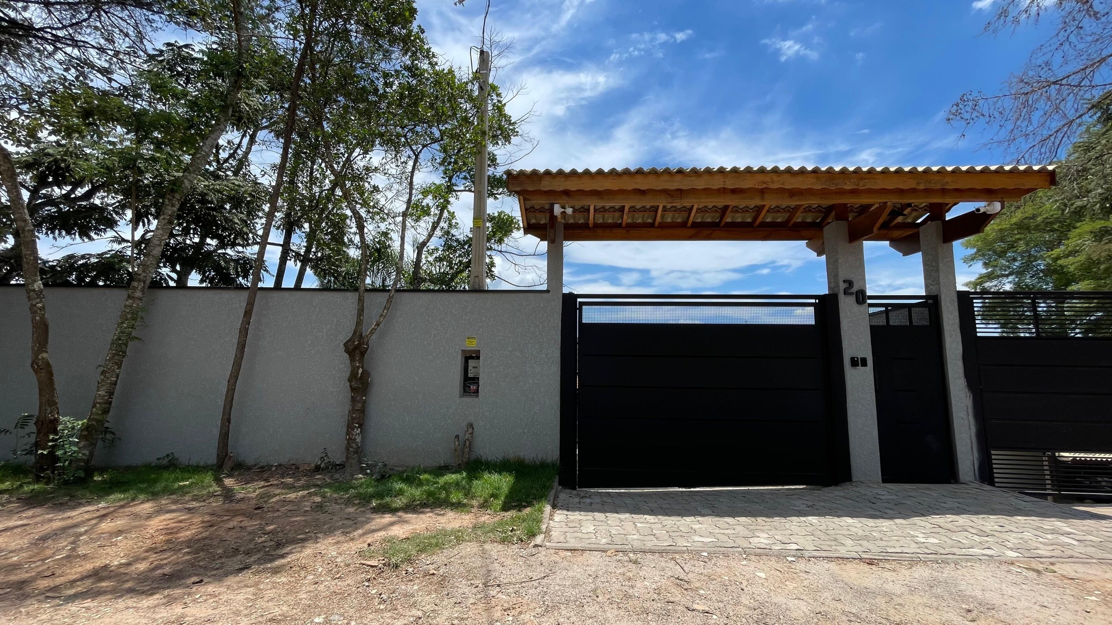 A gated entrance with a covered porch, a concrete wall, and a metal gate.