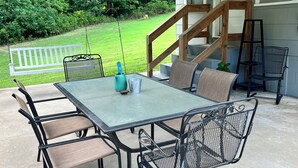 An outdoor patio with a table and chairs, a swing, and a view of a grassy area. - Charming 2-bedroom house in peaceful Cunningham (Cunningham)