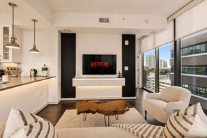 Ein modernes Wohnzimmer mit einem Flachbildfernseher, einem Holztisch und einem Sofa.