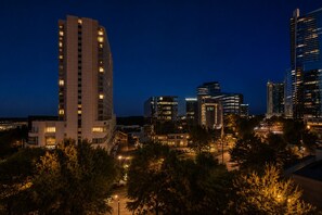 A nighttime cityscape with modern buildings, including a prominent high-rise hotel and several other commercial structures. - Buckhead Luxury 1BR - Lenox City View - Free Parking (Atlanta)