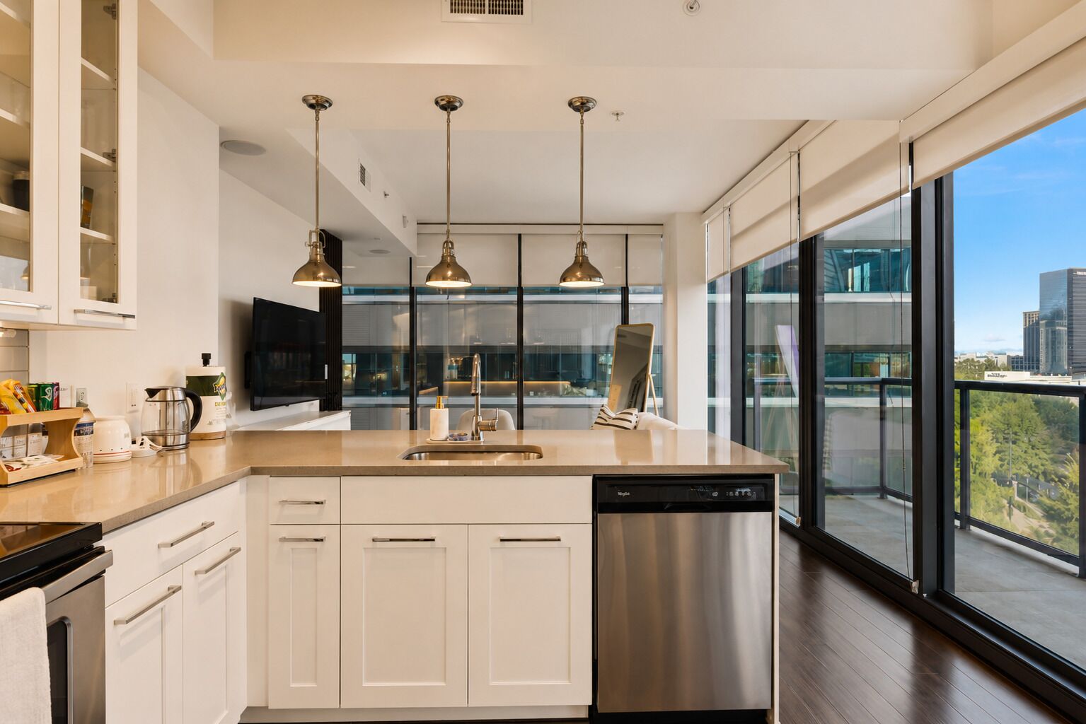 A modern kitchen with a dishwasher, a coffee maker, and a flat-screen TV.