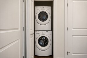 A compact, two-door laundry room with a modern, white washing machine and dryer. - Buckhead Luxury 1BR - Lenox City View - Free Parking (Atlanta)