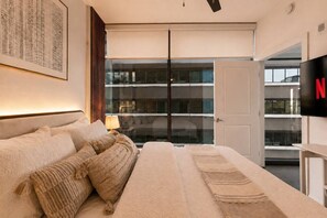 A modern hotel room with a large bed, a flat-screen TV, and a view of the city through large windows. - Buckhead Luxury 1BR - Lenox City View - Free Parking (Atlanta)