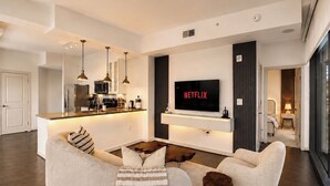 Ein modernes Wohnzimmer mit einer Couch, einem Couchtisch und einem an der Wand montierten Fernseher.