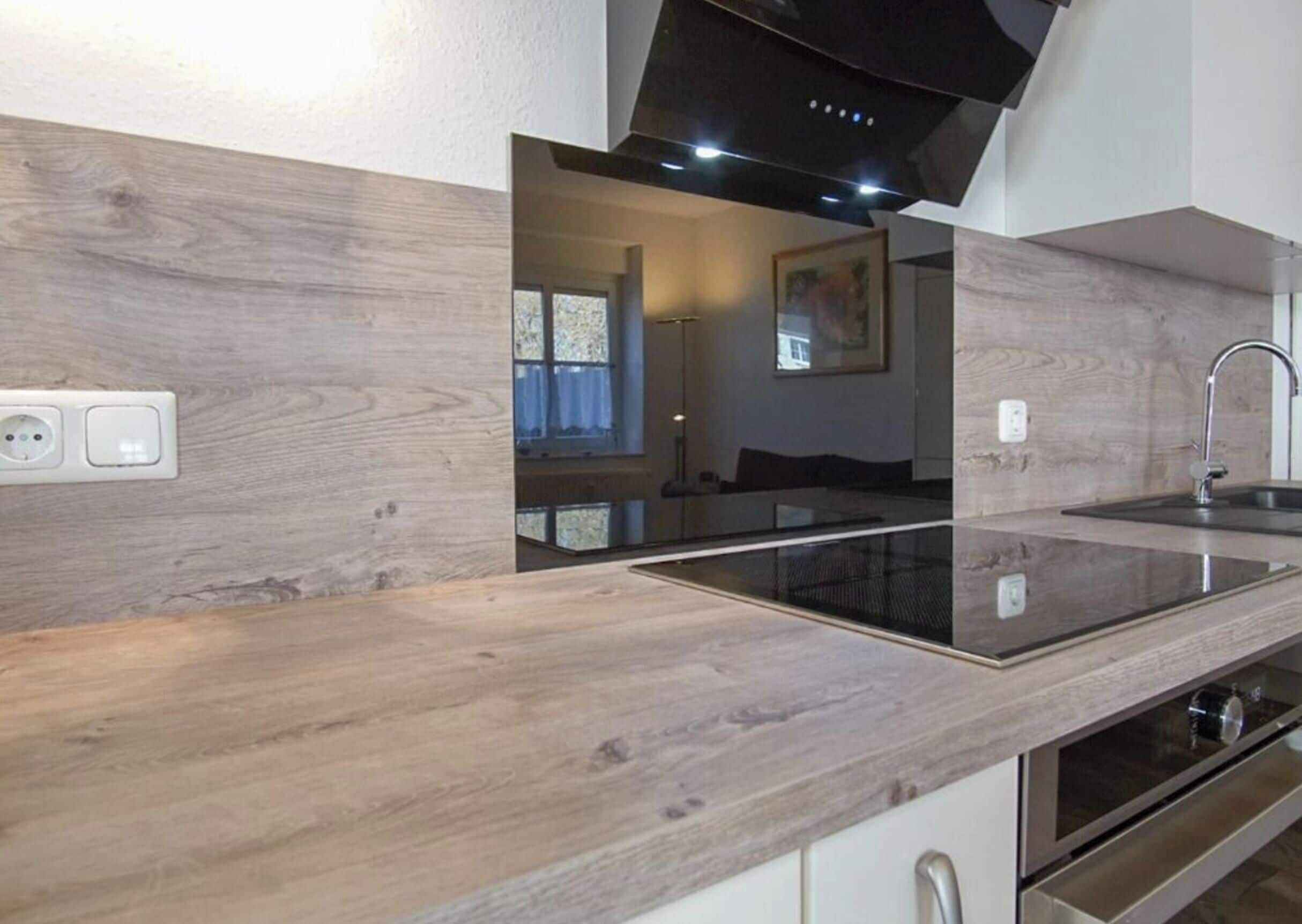 A modern kitchen with a wooden countertop, built-in oven, and a black range hood.