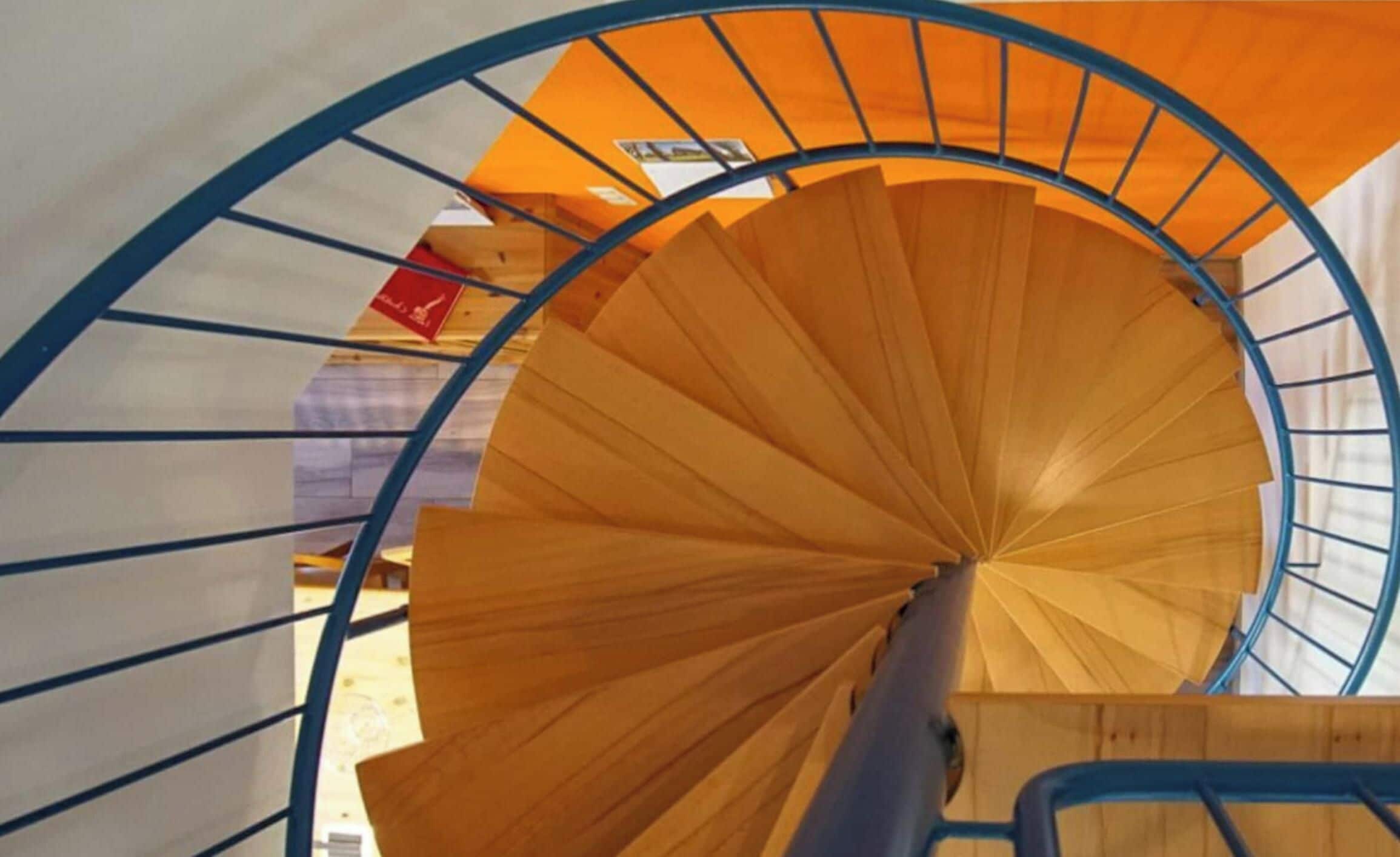 A spiral staircase with a wooden finish and blue metal railings.