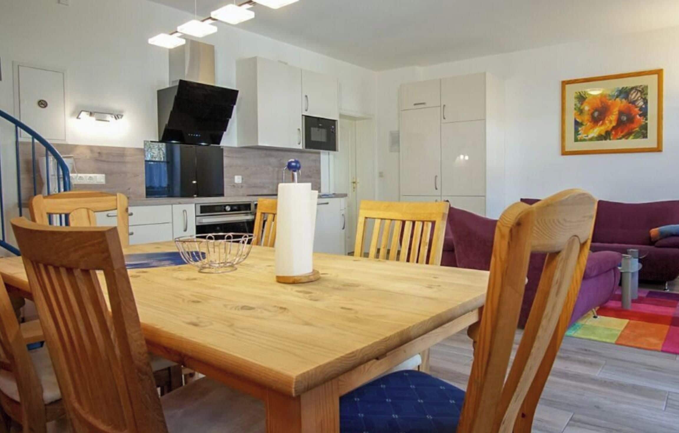 A modern kitchen with white cabinets, a black microwave, and a wooden dining table with chairs.
