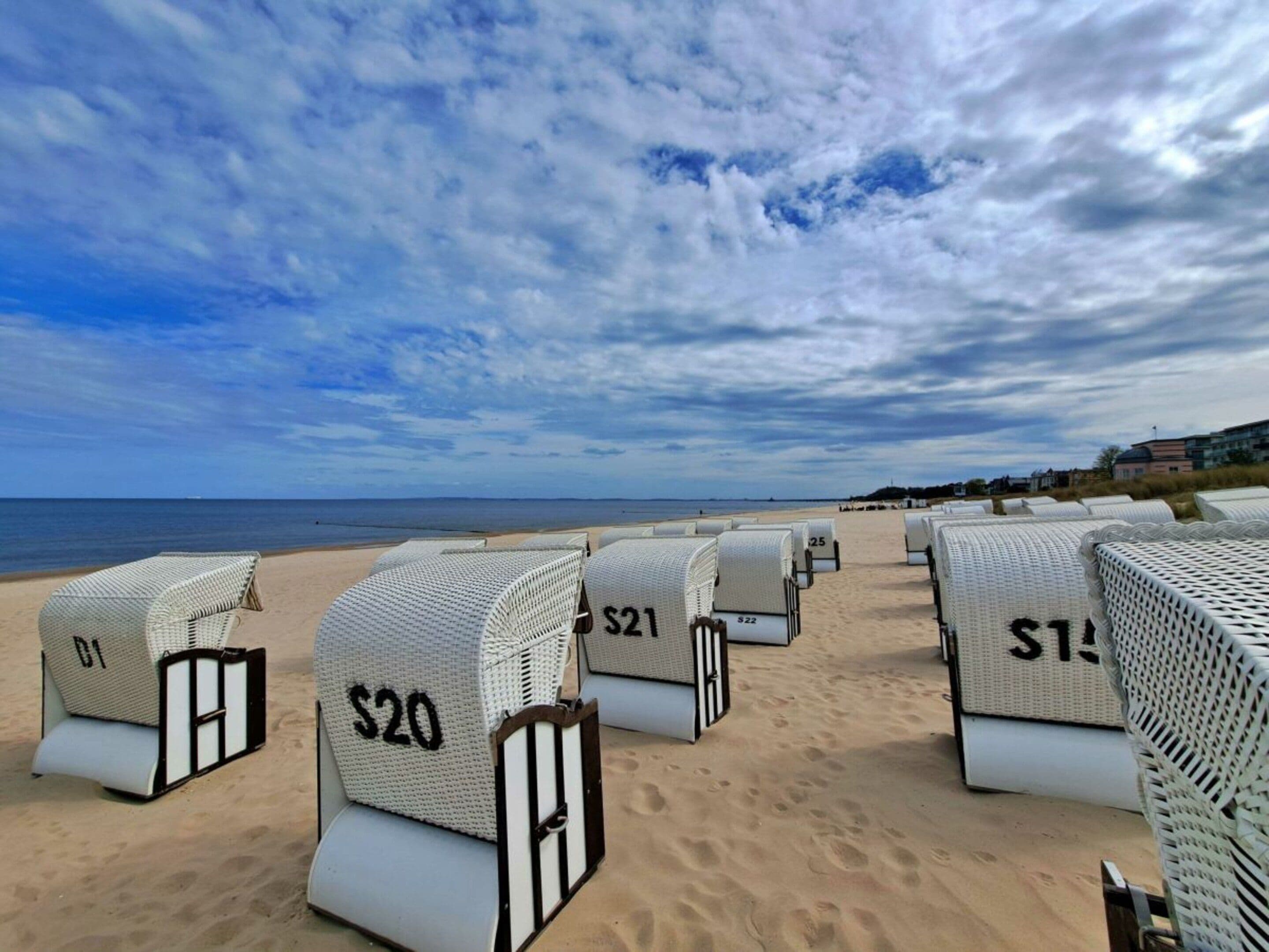 Chambres d’hôtel situées en bord de mer, avec des numéros sur les portes, disposées en rangées face à l’océan.