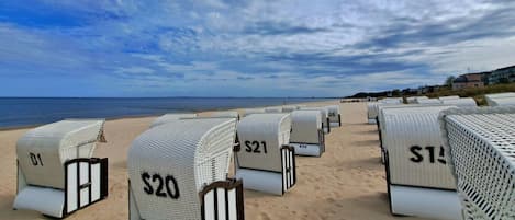 Beachside hotel rooms with numbers on the doors, arranged in rows facing the ocean.