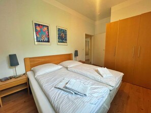 A double bed with two pillows, a bedside table with a lamp, and a wardrobe with sliding doors. - Villa Waldstrasse 03 (Heringsdorf)