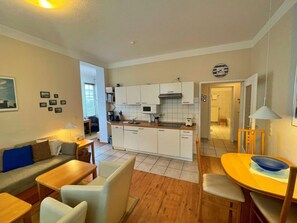 A compact living space with a kitchenette, a dining area, and a seating area with a sofa and chairs. - Villa Waldstrasse 03 (Heringsdorf)