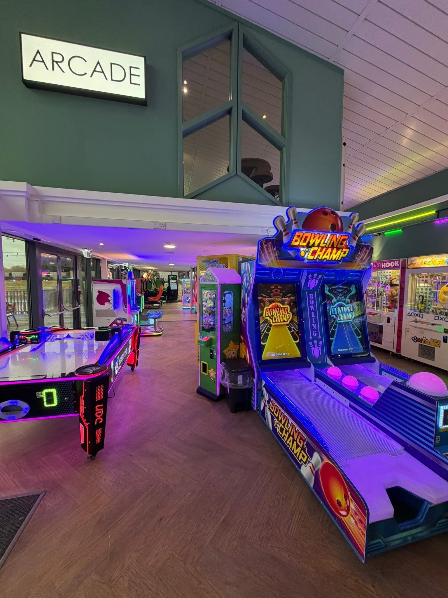 An indoor arcade with various gaming machines, including bowling and claw machines.
