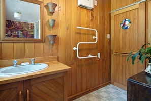 Ein Badezimmer aus Holz mit Waschbecken, Spiegel und Duschbereich.