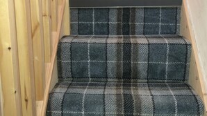 Un escalier recouvert d’une moquette à carreaux et doté d’une rampe en bois.