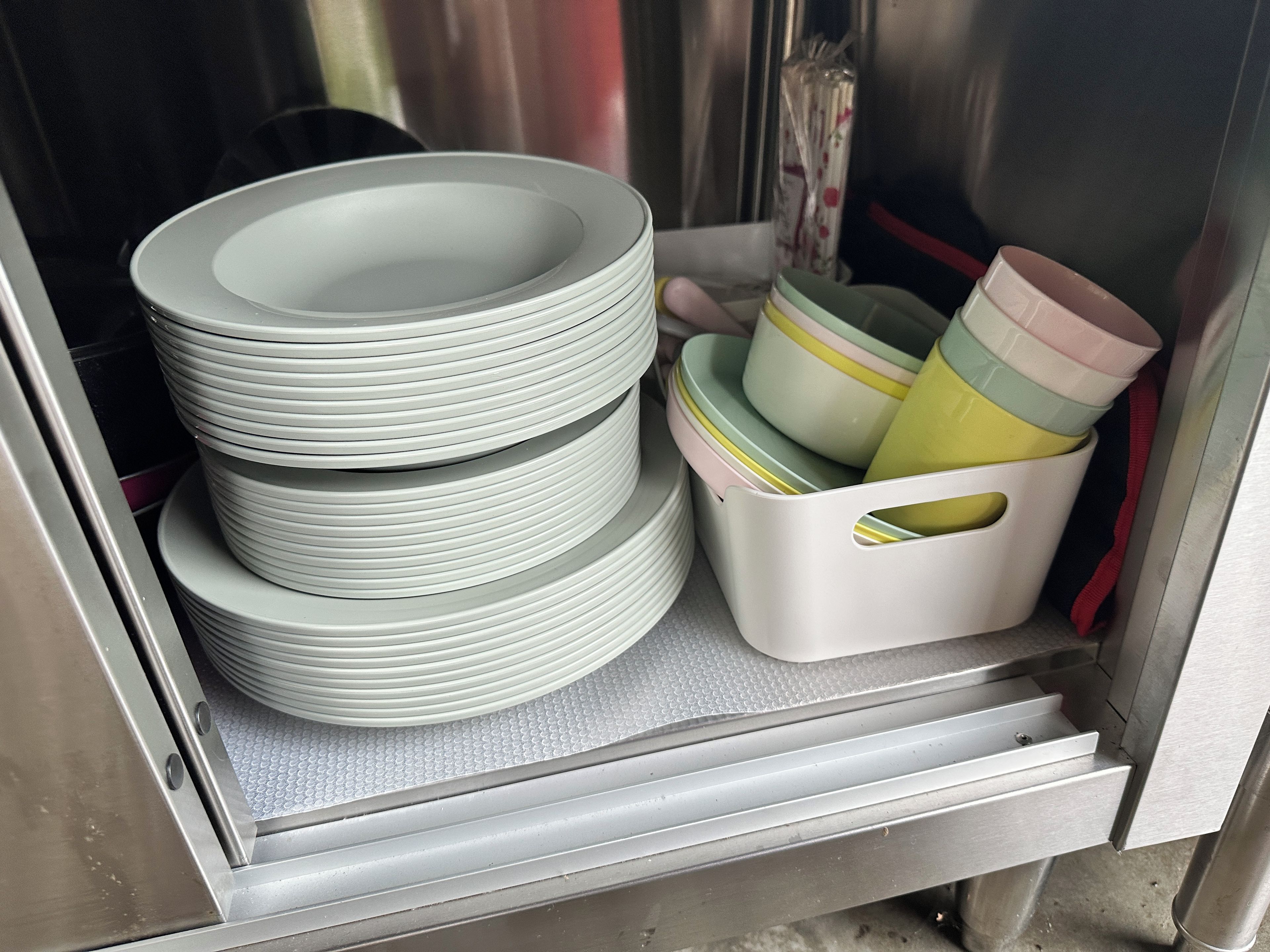 Un espace de rangement où sont empilées des assiettes et des bols.