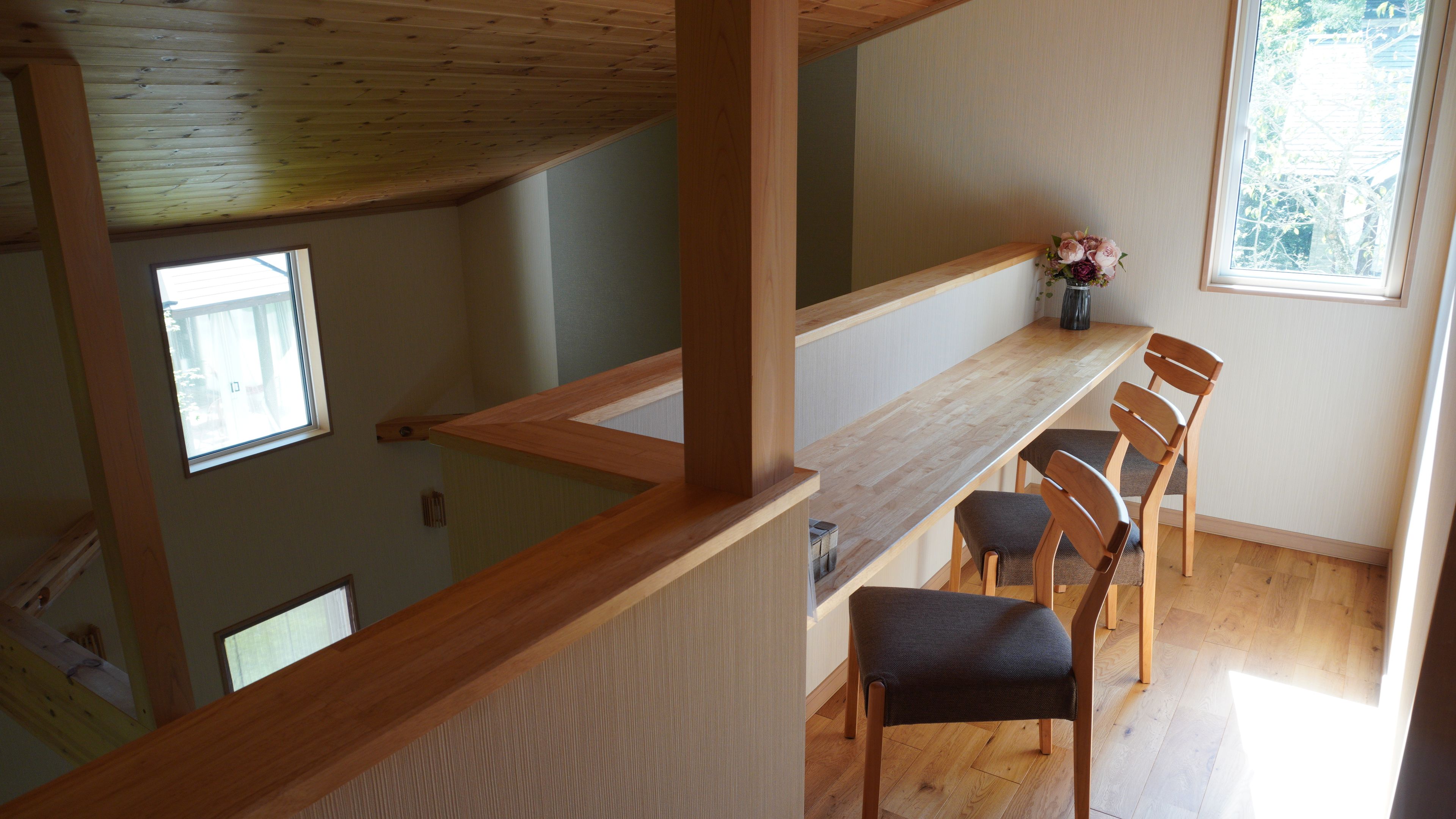 Un comedor con una mesa y sillas de madera, un florero con flores y vistas al exterior a través de una ventana.